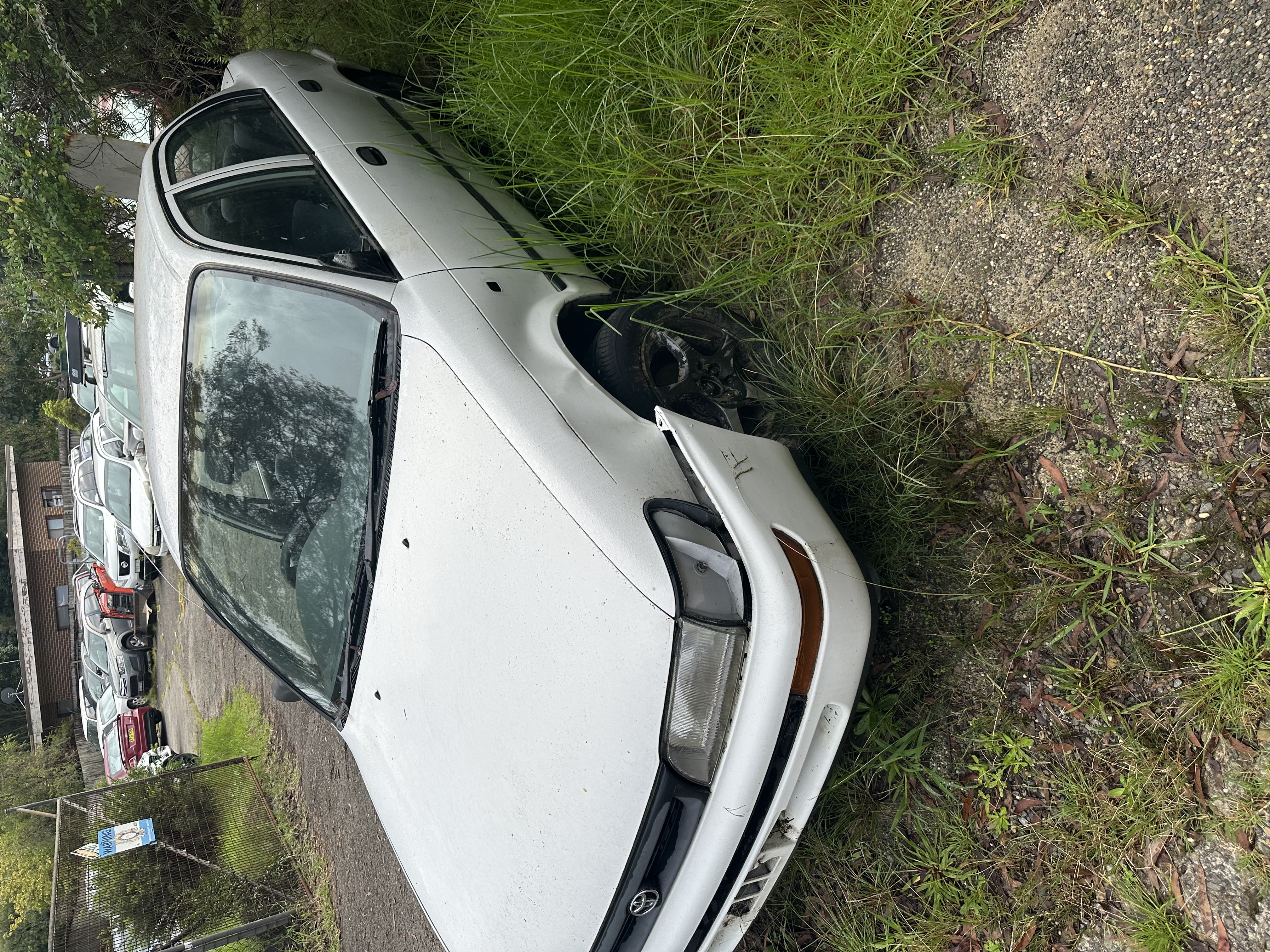 Front of a rusty abandoned car on sandy ground